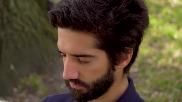 Gros plan portrait de bel homme avec barbe et cheveux noirs en plein air — Video