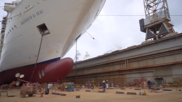 Feeport, Grand Bahama - Mar 13, 2019: Werknemers in de buurt van Royal Caribbean cruise schip Grandeur van de zeeën in het droogdok — Stockvideo