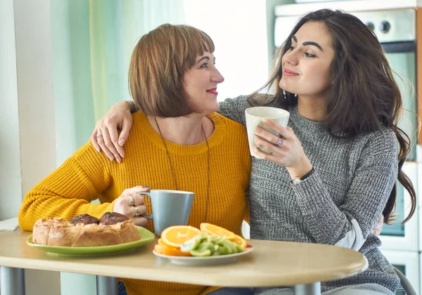 Anne ve kızı mutfakta çay içiyor.