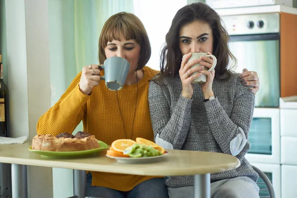 Anne ve kızı mutfakta kek ile çay içiyor
