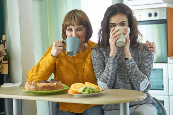 Kızı ve anne kameraya bakarak rahat mutfakta çay içmek