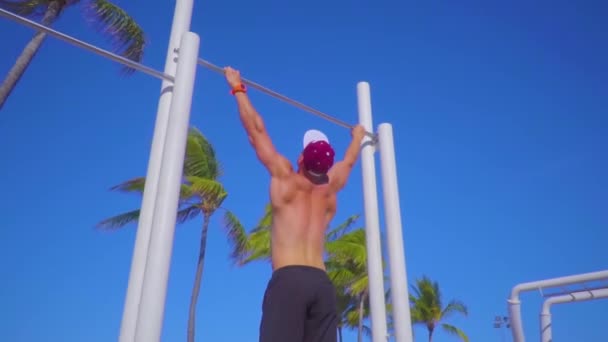 Joven musculoso haciendo ejercicio en barra horizontal al aire libre — Vídeos de Stock