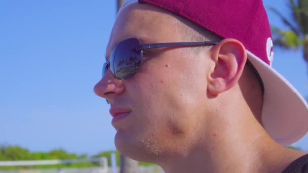 Portrett av en ung mann med solbriller og hette. – stockvideo