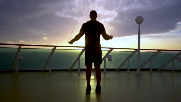 Silhouette du sportif fait un exercice avec une corde sautante tournée au lever du soleil — Video