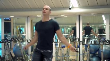 Genç sporcu spor salonunda ip atlama egzersizi yapıyor.