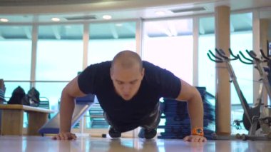 Genç sporcu spor salonunda el çırparak şınav çekiyor.