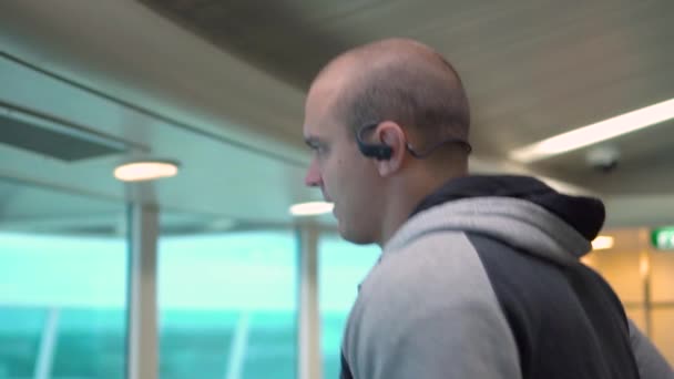 Портрет молодого спортсмена, що бігає в спортзалі в навушниках — стокове відео