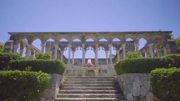 Man athlete stands on his head among antique columns — Stock Video