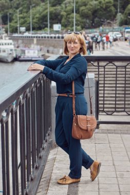 Nehir kıyısında duran orta yaşlı kadının portresi