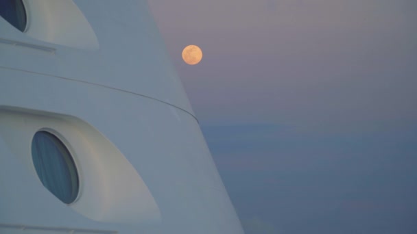 Луна за иллюминаторами круизного лайнера, закат в море — стоковое видео