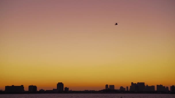 Policejní vrtulník létá nad mořem vedle pobřeží Floridy při západu slunce — Stock video