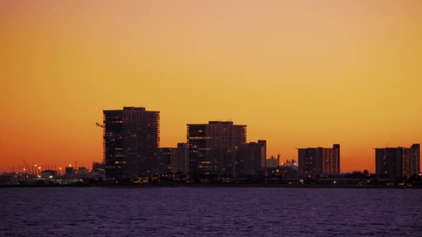 Samolot startuje za budynkami miasta na pomarańczowym niebie w Fort Lauderdale na Florydzie — Wideo stockowe