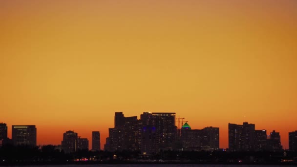 Paisaje nocturno de la ciudad con edificios sobre un colorido fondo de cielo al atardecer — Vídeo de stock