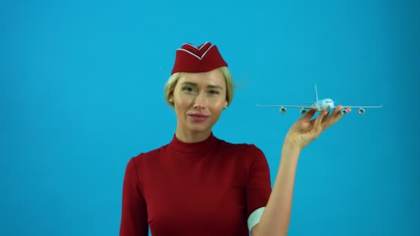 Die Stewardess lächelt mit einem Spielzeugflugzeug in der Hand — Stockvideo