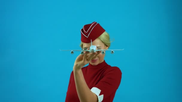 Стюардесса улыбается с игрушечным самолетом в руках — стоковое видео