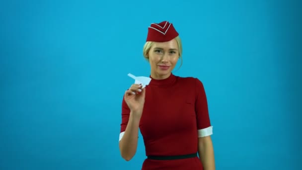 Die Stewardess lächelt mit einem Spielzeugflugzeug in der Hand — Stockvideo