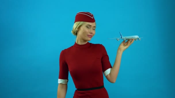 Die Stewardess lächelt mit einem Spielzeugflugzeug in der Hand — Stockvideo