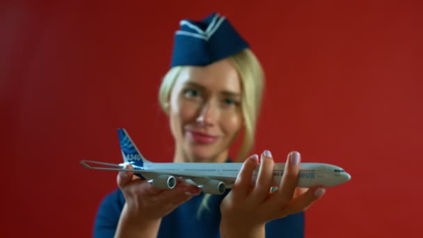 Flygvärdinnan leende med en leksak plan i hennes händer — Stockvideo
