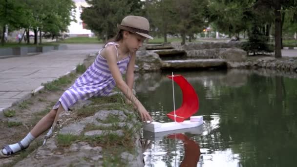 Uma Menina Lança Navio Com Uma Vela Vermelha Lagoa Cidade — Vídeo de Stock