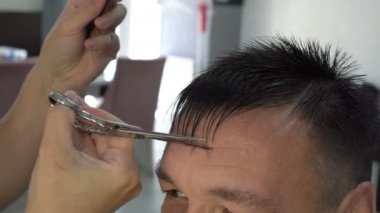 Kuaför stilist bir kuaför dükkanında insan saçı keser. Makas ile onun patlama keser. Saç Bakımı. Önden görünüm. Yakın çekim, yüksek detay. 4k, 25 fps