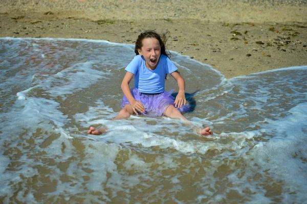 보라색 드레스에 화창한 날에는 해변에 모래에 그녀는 웨이브 — 스톡 사진