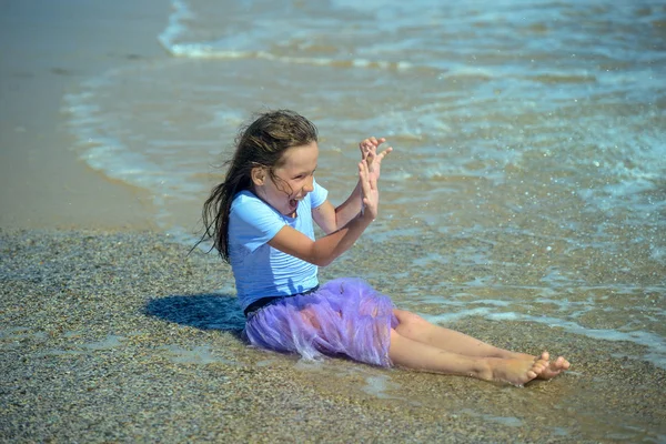 앉아서 해변에 보라색 드레스에 그녀는 다가오는 웃음에 그녀의 손으로 자신을 — 스톡 사진