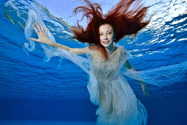 Girl Red Hair White Dress Swims Plays Underwater Blue Background — Stock Photo, Image