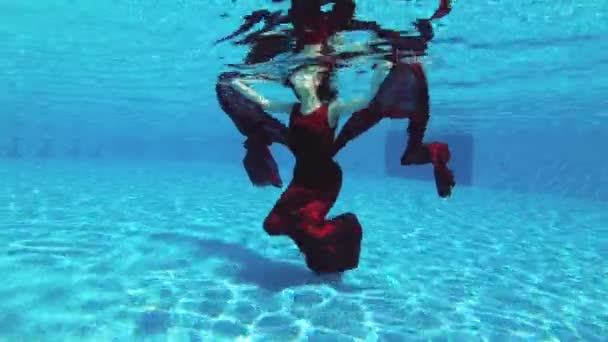 一个美丽的红头发的新娘女孩在一个阳光明媚的日子 在一个蓝色的背景下 穿着红色连衣裙在室外游泳池里游泳和摆姿势 慢动作 Fps — 图库视频影像