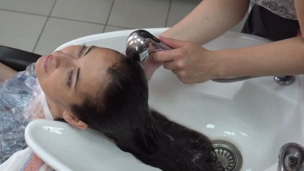 头发护理 一位女美发师在美容院洗一个黑发女孩的头 洗掉她头发上的颜料 关门了从顶部的视图 Fps — 图库视频影像