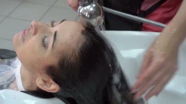 Kuaför stilist başını yıkar ve güzellik salonunda boyama sonra saç esmer kızdan boya off yıkar. Saç Bakımı. Yakın çekim. Üstten görünüm. 4 k. 25 fps.