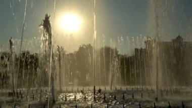 Günbatımı şehir çeşmede genel bakış. Su akarsu müzik ritmine göğe Şehir Park arka planda sarı bir günbatımı sinek. 4k, 25 fps.