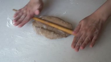 Kadın el kahverengi hamur beyaz bir tablo ve o a tava keki rulo başlar bir ahşap oklava kneads. Yakın çekim, yüksek detay. Üstten görünüm. 4 k. 25 fps.