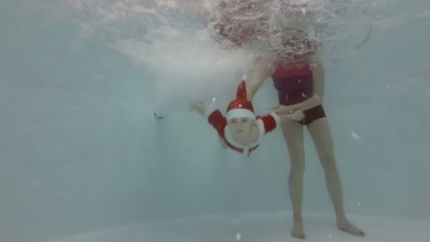 Мама Допомагає Маленьким Хлопчиком Одягнені Санта Клаус Пірнути Під Водою — стокове відео