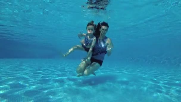 Счастливая Мама Маленькой Дочкой Плавает Ныряет Воду Бассейне Полосатых Купальниках — стоковое видео