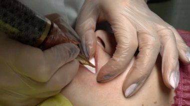 Son derece yakın çekim kozmetik prosedürler kalıcı makyaj dudaklar. Güzellik uzmanı bir genç kız bir güzellik salonda dudaklarında iğneyle boya uygulanır. 4 k. 25 fps.