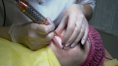 Kozmetik prosedür. Kalıcı dudak makyaj. Kız güzellik salonunda dudakları bir düzeltme yapmak. Yakın çekim. Üstten görünüm. 4 k. 25 fps.