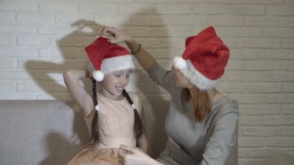 Older Sister Helps Little Girl Put Santa Hat Her Head — Stock Video