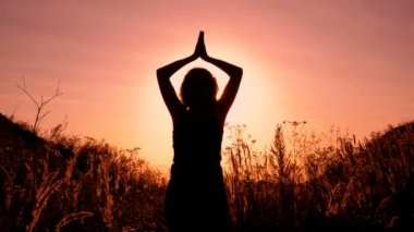 Bir adam kızıl gökyüzü ve parlak Kanlı günbatımı arka plan üzerinde siyah silüeti. Anlamına gelir ve yavaş yavaş ellerini başını bağlanır. Kavramsal gerçekçilik. Yakın çekim. Alt görünümü. 4 k. 25 fps.