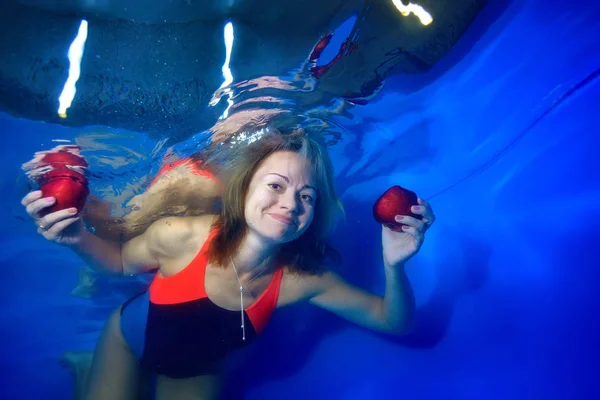 Bella Ragazza Galleggiante Sotto Acqua Uno Sfondo Blu Tenendo Mele — Foto Stock