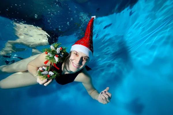 Wesoła Dziewczyna Pływa Pod Wodą Czerwony Kapelusz Świętego Mikołaja Trzymając — Zdjęcie stockowe