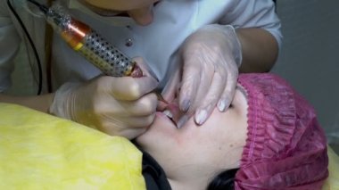Kalıcı dudak makyaj Güzellik Salonu prosedürü. Güzellik uzmanı boya bir microneedle genç bir kızla dudaklarında hıyarlar. Microblading. Yakın çekim. 4 k. 25 fps.