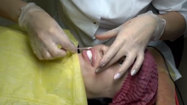 Doktor Şevval özçelik güzellik güzellik salonu kalıcı makyaj dudaklarında prosedürü sonra kızın dudakları yağlar. Üstten görünüm. Yakın çekim. 4 k. 25 fps.