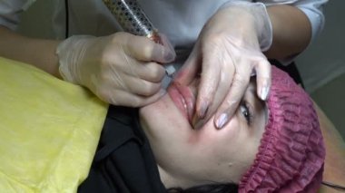 Kız Güzellik Salonu kalıcı makyaj dudaklarında yapıyor. O kanepede yatıyor ve dudaklarını kabul edilir. Microblading. Yakın çekim. Üstten görünüm. 4 k. 25 fps.