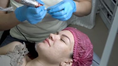 Ana Şevval özçelik güzellik kızın kaş davranır ve kalıcı kaş makyaj Güzellik Salonu işlemi sırasında bir iğne siyah boya ile bıçakladı. Kaşları Microblading. Yakın çekim. 4 k. 25 fps