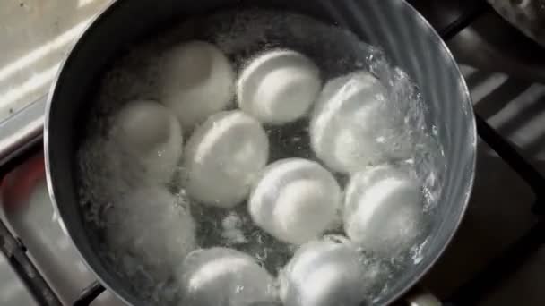 Beaucoup d'œufs blancs se trouvent et bouillent dans une casserole en métal dans de l'eau bouillante. Ferme là. La vue du haut. 4K. 25 ips — Video