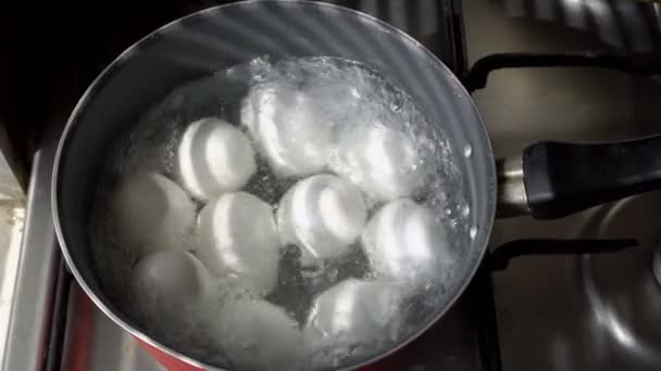 白い卵は、ガスストーブの上の鍋に沸騰したお湯でゆでています。クローズ アップ。頂上からの眺め。4 k. 25 fps — ストック動画