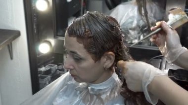 Saç Kuaför Salonu boyama prosedürü close-up. Bayan Kuaför kızın saçının boya bir fırça ile uygulanır. Saç Bakımı. Yan görünümü. 4 k. 25 fps.
