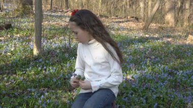Sevimli küçük kız kardelen bahar orman parlak güneşli bir günde toplar. Yakın çekim. Portre. 4 k. 25 fps.