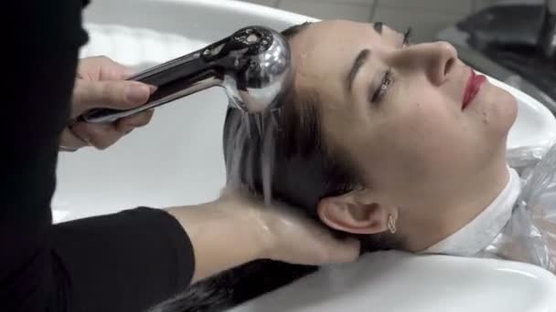 Gros plan sur le lavage de la tête d'une Orientale dans un salon de coiffure après avoir coupé et colorié ses cheveux. Soins capillaires. Ferme là. 4K. 25 ips . — Video