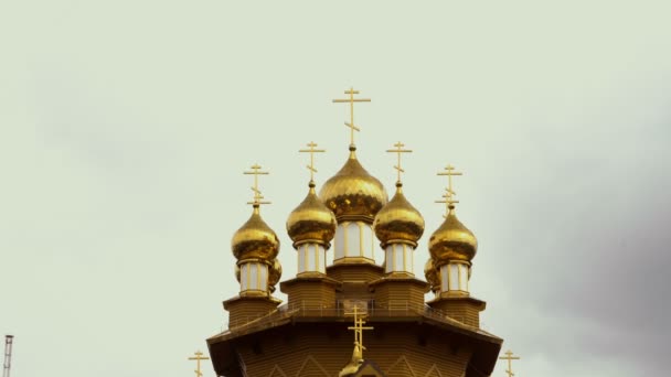 Gyllene kupoler med kors på en gammal trä kristen kyrka mot en dramatisk himmel. Ryssland, Belgorod. Koncept. Närbild. 4k. 25 fps — Stockvideo